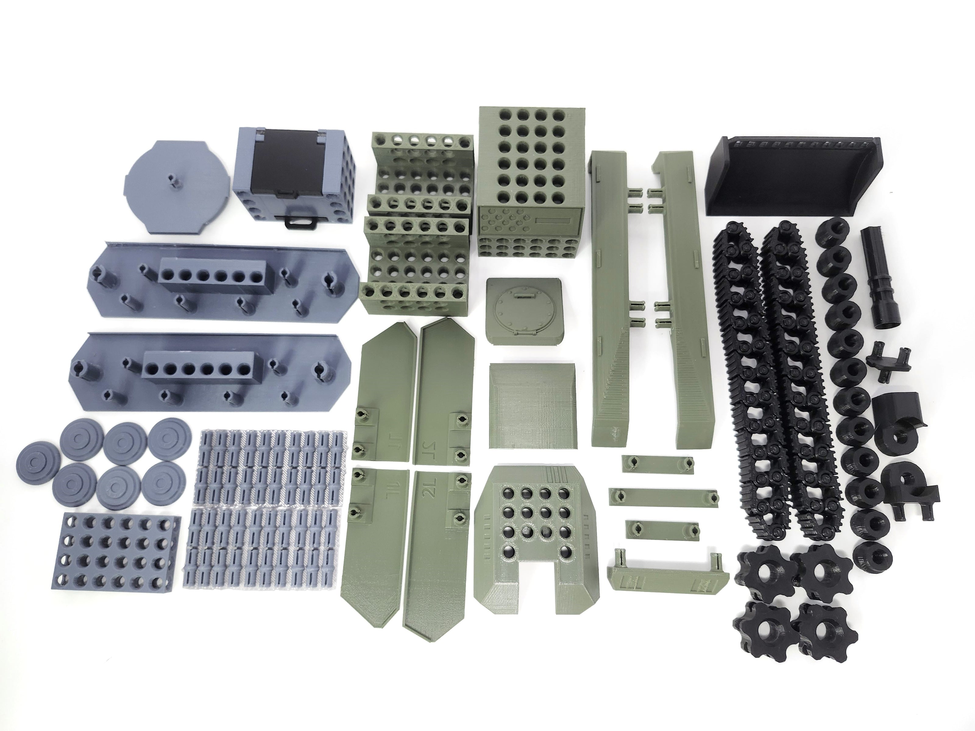 A collection of unassembled parts of a toy tank, including various tracks, guns, and other accessories in gray, green, and black colors.